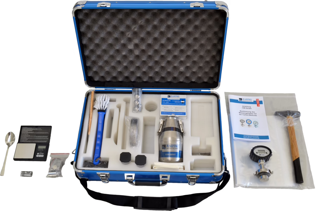 WOLFF_Dummy_84546_CCM-instrument Alu Business Pro_2025-08 Offener blauer Transportkoffer mit Schaumstoffeinlage, der ein Feuchtemess-Kit enthält. Sichtbar sind ein Metall-Probenbehälter mit Aufschrift 'RADTKE MESSTECHNIK', eine Langbürste, eine kleine digitale Waage mit Löffel, eine Bedienungsanleitung, ein Druckmanometer, ein Holzhammer, Batterien, verschiedene versiegelte Kleinteile und mehrere schwarze Schutzkappen, alles sauber in ausgeschnittenen Schaumstofffächern angeordnet.