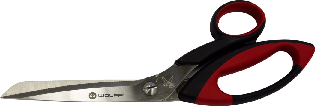 WOLFF_Dummy_15659_34831_15652_universal carpet shears_2025-08 Eine große Schere aus rostfreiem Stahl mit gezahntem Schneideblatt, ergonomischen Kunststoffgriffen in Schwarz und Rot und dem Schriftzug 'WOLFF' auf der Klinge. Die Klingen sind mit einer Schraube verbunden und leicht angewinkelt; der Griff hat eine weiche Einlage für besseren Halt. Fotografiert vor weißem Hintergrund.