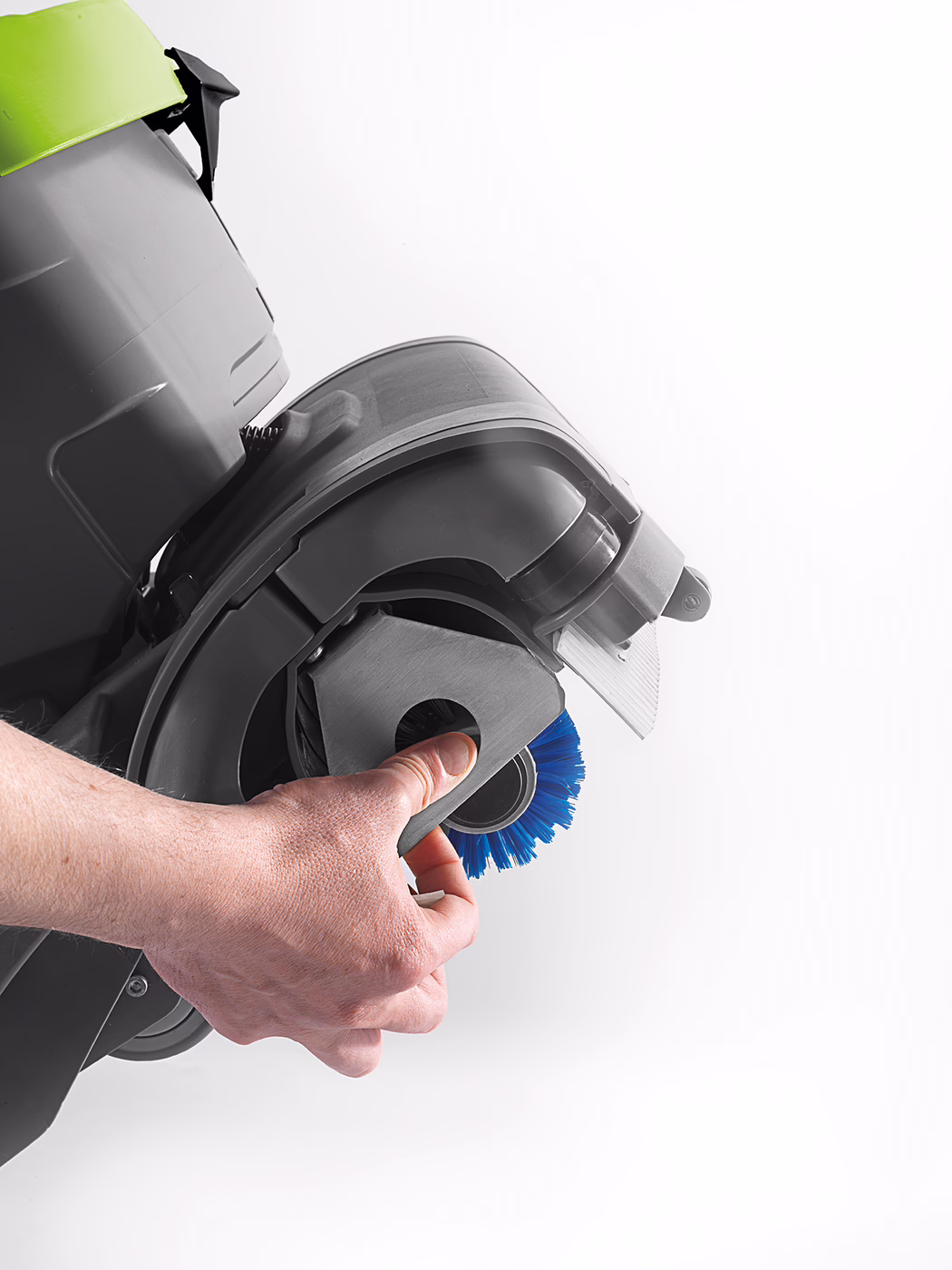 WOLFF_Product_detail_Cleanfox_Bürstenwechsel_2017 Nahaufnahme einer Hand, die ein abnehmbares Bürstenmodul eines Bodenreinigers hält: graues Kunststoffgehäuse, blaue Rundbürste und am Rand sichtbare limonengrüne Abdeckung vor weißem Hintergrund.