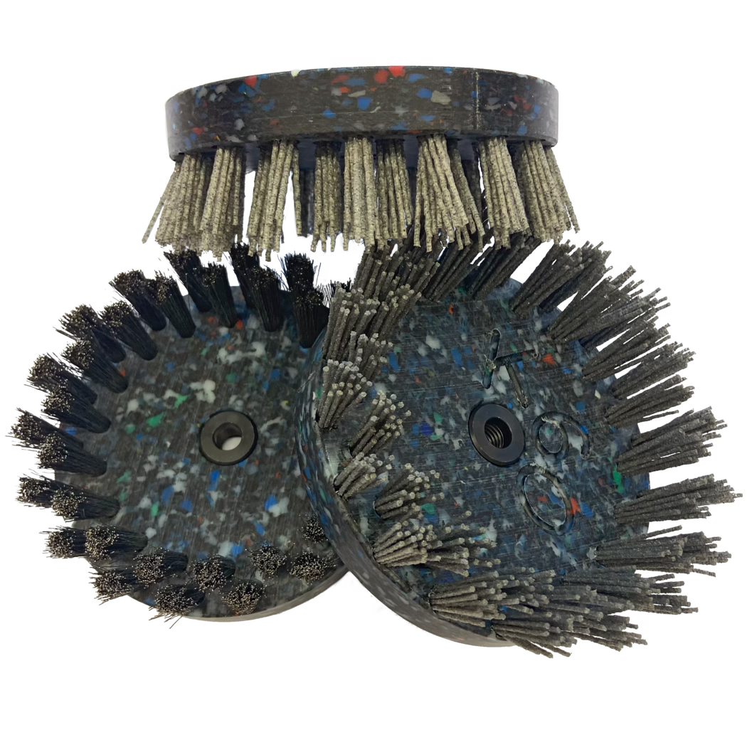 Derendinger_Dummy_162628_Bürstteller-Edelstahl-150 mm Ein Set von drei kreisförmigen Bürsten mit unterschiedlichen Borstenlängen und -dichten. Die Bürsten haben ein dunkles, gesprenkeltes Design, das aus verschiedenen Farben wie Grau, Blau und Rot besteht. Die Borsten sind metallisch und aus Kunststoff, sodass sie für verschiedene Arten von Reinigungsaufgaben geeignet sind. Die obere Bürste hat kürzere Borsten, während die beiden darunter längere, dickere Borsten haben, was auf ein robustes Design hinweist, das für den intensiven Gebrauch gedacht ist.