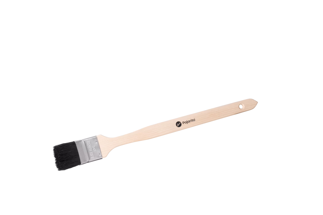 Pajarito_Dummy_Radiator brush Nature Mix P-Line_179064_179065_179066_179067_2024-02 Langer Maler- bzw. Flachpinsel mit naturfarbenem, schlankem Holzgriff, fotografiert vor weißem Hintergrund. Der helle Buchenholzgriff ist ergonomisch geformt, besitzt am Ende ein kleines rundes Aufhängeloch und trägt das schwarze Markenlogo 'pajarito' auf der Stange. Eine gecrimpte silberne Metallzwinge hält dichte, kurze schwarze Borsten; die Zwinge ist mit '50' und 'ROSTFREI' geprägt, was auf eine 50-mm-Breite und rostfreien Stahl hinweist. Der Pinsel liegt diagonal im Bild, zeigt Holzmaserung, saubere Borstenenden und die Metallfassung; er wirkt neu und unbenutzt und eignet sich für Kanten-, Leisten- und Detailarbeiten.