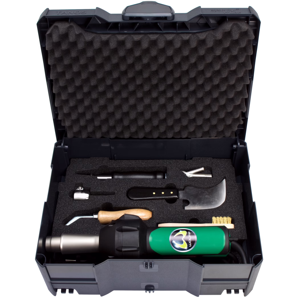 WOLFF_Dummy_82643_LeisterTriac Set AT_2025-08 Offener Hartplastik-Werkzeugkoffer mit wabenförmigem Schaumstoff im Deckel und maßgefertigten Schaumeinsätzen, die einen grünen Heißluftföhn und mehrere Handwerkzeuge wie eine gebogene Klinge, ein Werkzeug mit Holzgriff, Metallaufsätze und eine Messingbürste halten.