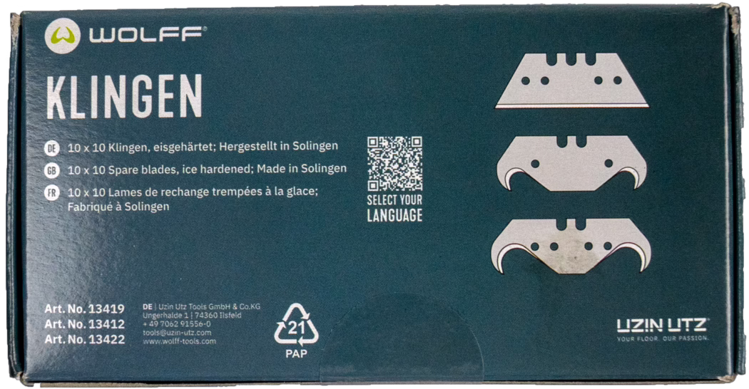 WOLFF_Dummy_13419_13421_blade box_2025-08 Detailaufnahme einer rechteckigen Pappschachtel mit Wolff-Ersatzklingen für Bodengeräte. Die dunkelpetrolfarbene Verpackung zeigt oben links das Markenlogo 'WOLFF' und links das große weiße Wort 'KLINGEN'. Rechts sind drei stilisierte Klingenabbildungen gedruckt; dazwischen befindet sich ein kleiner QR-Code mit der Aufschrift 'SELECT YOUR LANGUAGE'. Mehrsprachige Produktinformationen nennen in Deutsch, Englisch und Französisch '10 x 10 Klingen, eisgehärtet; Hergestellt in Solingen'. Unten links stehen drei Artikelnummern und Kontaktdaten des Herstellers, in der unteren Mitte ist das Recyclingzeichen '21 PAP' zu sehen. Die Schachtelkanten zeigen leichte Gebrauchsspuren. Gesamtansicht einer sauberen Produktverpackung vor weißem Hintergrund.